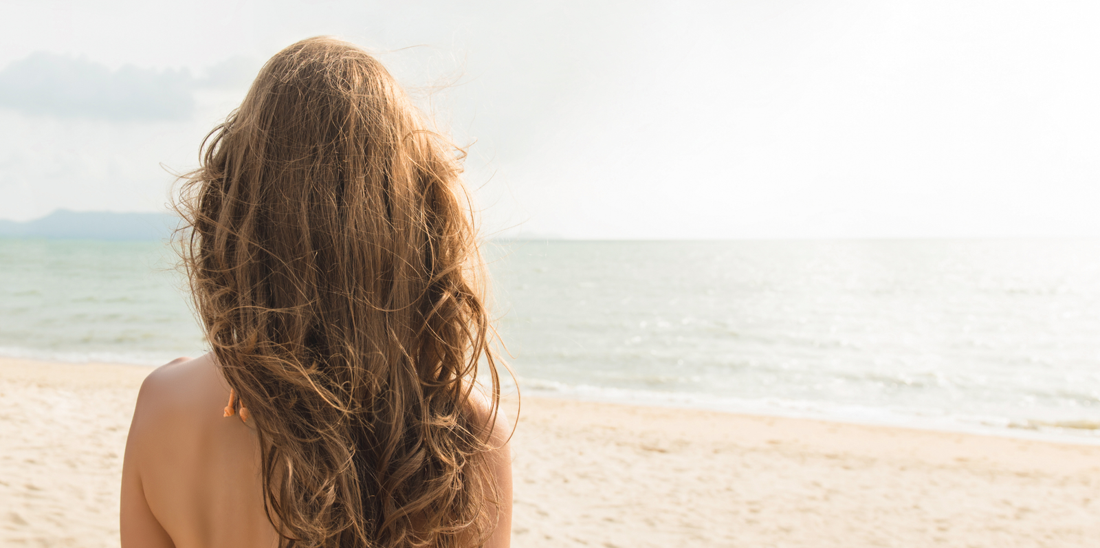 Mujer en la playa practicando mindfulness y actividades de bienestar